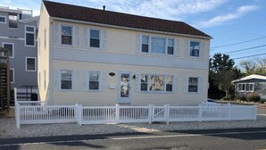A two-story house with a white picket fence, a front door, and a small porch. - Oceanside, Duplex - 1st Flr Unit North Beach Haven, 20th St (Long Beach)