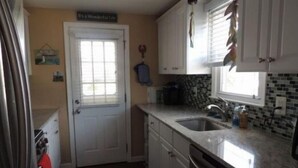 A compact kitchen with white cabinets, a double sink, and a dishwasher. - Oceanside, Duplex - 1st Flr Unit North Beach Haven, 20th St (Long Beach)