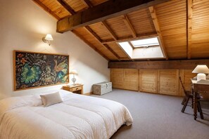 Quarto com uma cama grande, claraboia, paredes de madeira e um quadro.