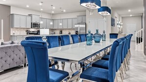 A modern kitchen with white cabinets, stainless steel appliances, and a large island with blue chairs. - 10BR house at Windsor Cay resort, clermont (Clermont)