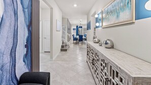 A hallway with a marble wall, a wooden console table, and a staircase leading to another room. - 10BR house at Windsor Cay resort, clermont (Clermont)