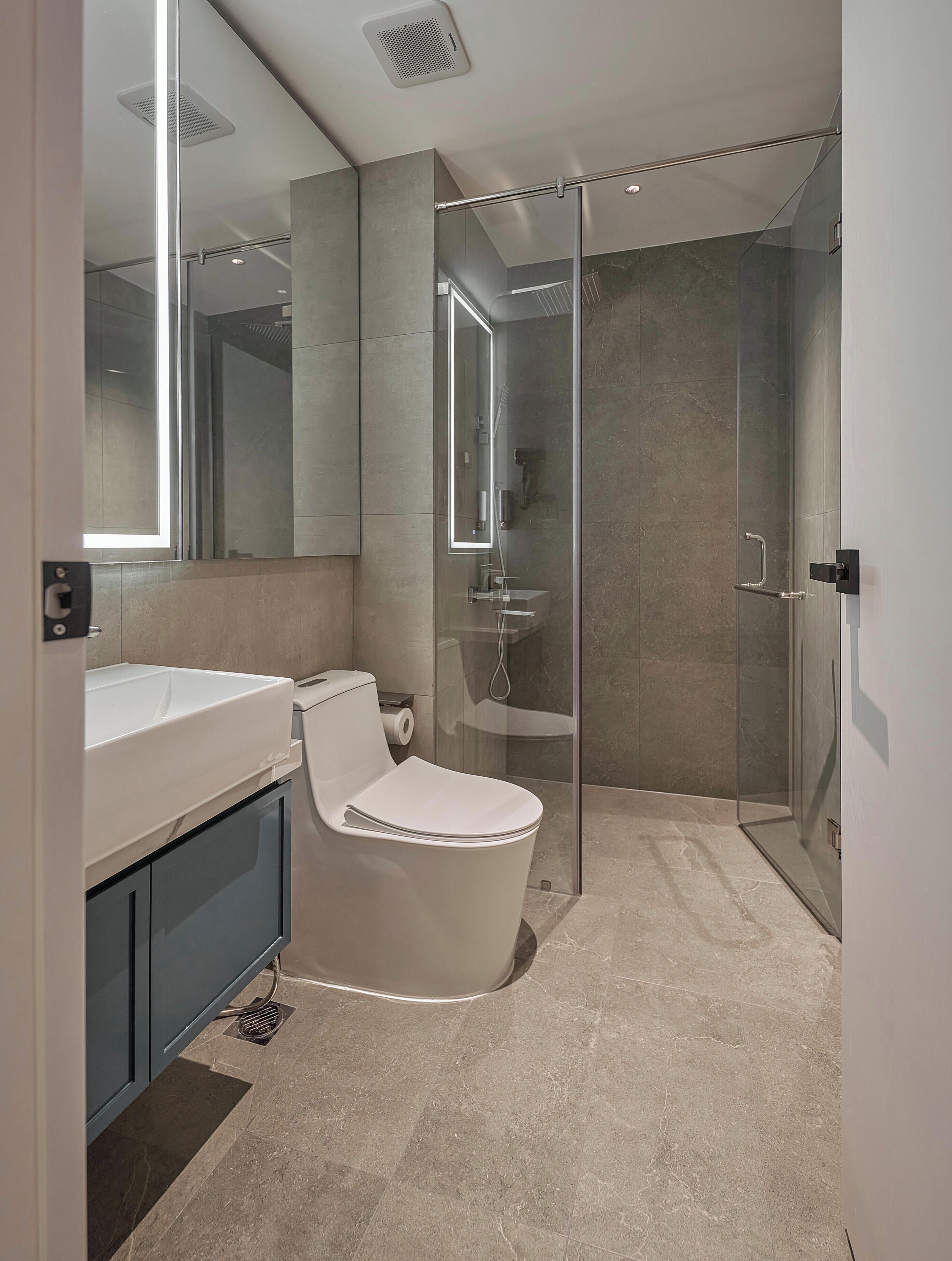 Une salle de bain moderne avec une douche à parois de verre, des toilettes blanches et un meuble-lavabo avec un miroir.