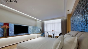 Une chambre d’hôtel moderne dotée d’un grand lit, d’un téléviseur à écran plat, d’une petite table avec des chaises et d’un panneau décoratif mural.