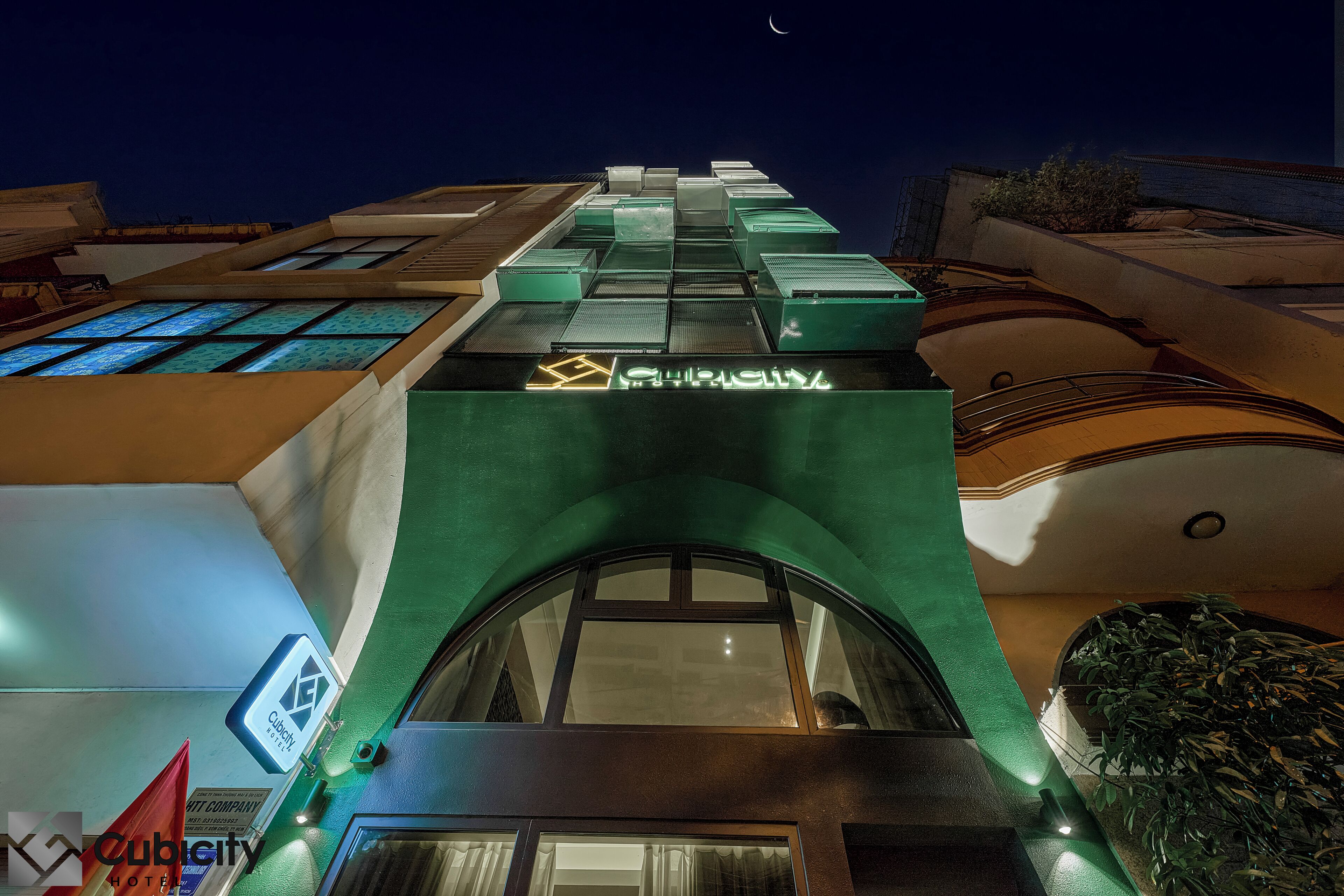 A hotel building with a modern design, featuring a prominent green facade and multiple windows.