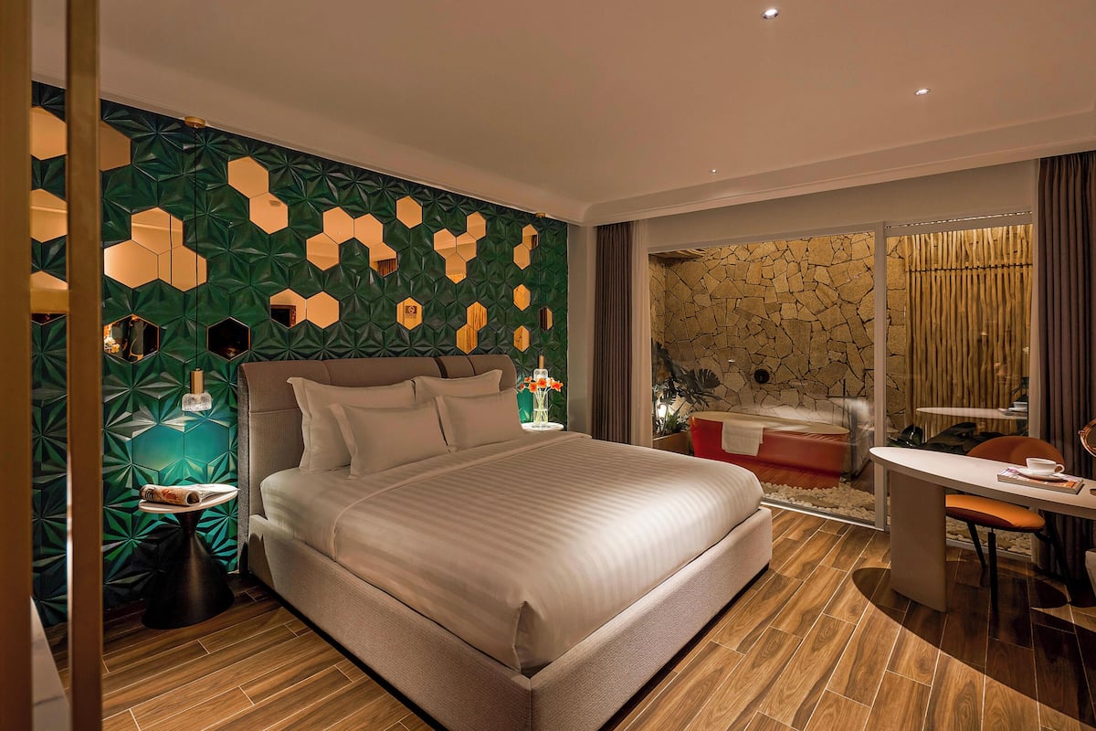 Quarto de hotel moderno com uma cama grande, uma escrivaninha e uma parede de pedra.