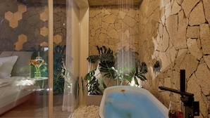 Une salle de bain moderne avec une baignoire rouge, des galets blancs et une cabine de douche en verre.
