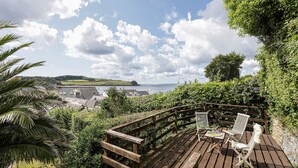 A wooden deck with a view of a coastal town, a wooden railing, and two white chairs. - Sail Loft (Marine Parade - St Mawes) (St Mawes)