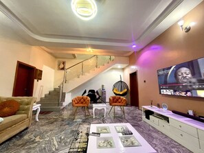 A living room with a staircase, a television, and a sofa. - Luxury 4 BR Apt w Parking, Magodo Estate (Lagos)