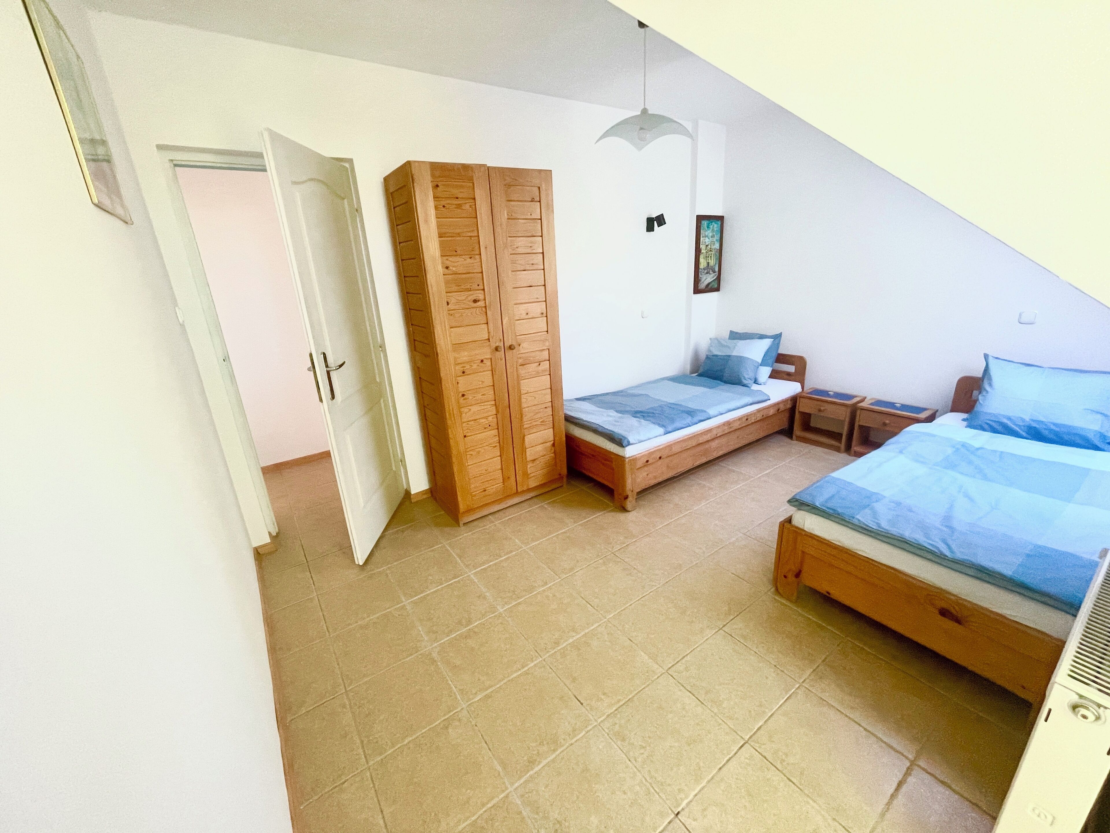 Een slaapkamer met twee bedden, een kledingkast, een plafondventilator en een deur.