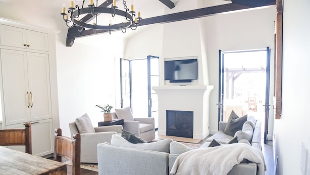 A spacious living room with a fireplace, a television mounted above it, and a large window providing natural light.