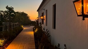 A pathway leading to a building with a white exterior and a hanging lantern.