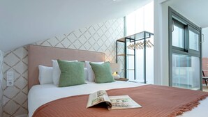 A modern hotel room with a large bed, a magazine on the bed, a nightstand with a lamp, and a window with a view of the city. - Genteel Home San Matías V (Granada)