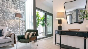 A modern living room with a sofa, armchair, floor lamp, console table, and a large mirror. - Genteel Home San Matías III (Granada)