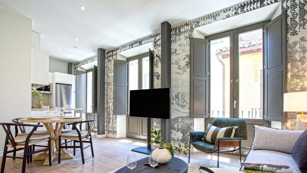 A modern living room with a dining area, a flat-screen TV, and a large window. - Genteel Home San Matías III (Granada)