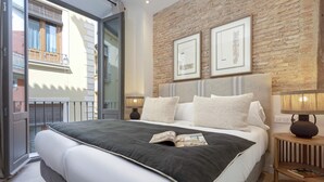 A bedroom with a large bed, a brick wall, and two framed pictures. - Genteel Home San Matías III (Granada)