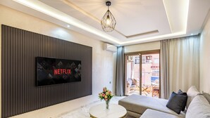 Ein modernes Wohnzimmer mit Flachbildfernseher, rundem Couchtisch, einer Couch und einer dekorativen Vase.