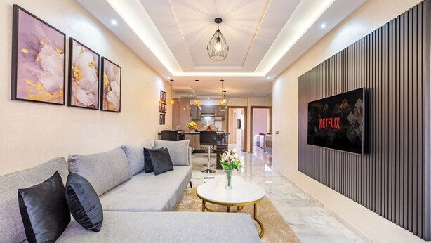 Ein modernes Wohnzimmer mit einer Couch, einem Couchtisch und einem an der Wand montierten Fernseher.