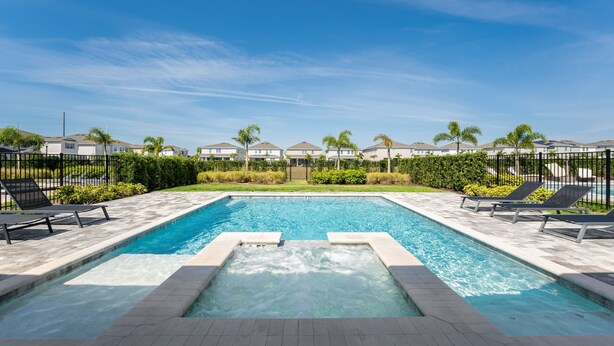 A rectangular swimming pool with a hot tub in the center, surrounded by lounge chairs and a fence. - Discover Your Inner Child  Encore Villa (Kissimmee)