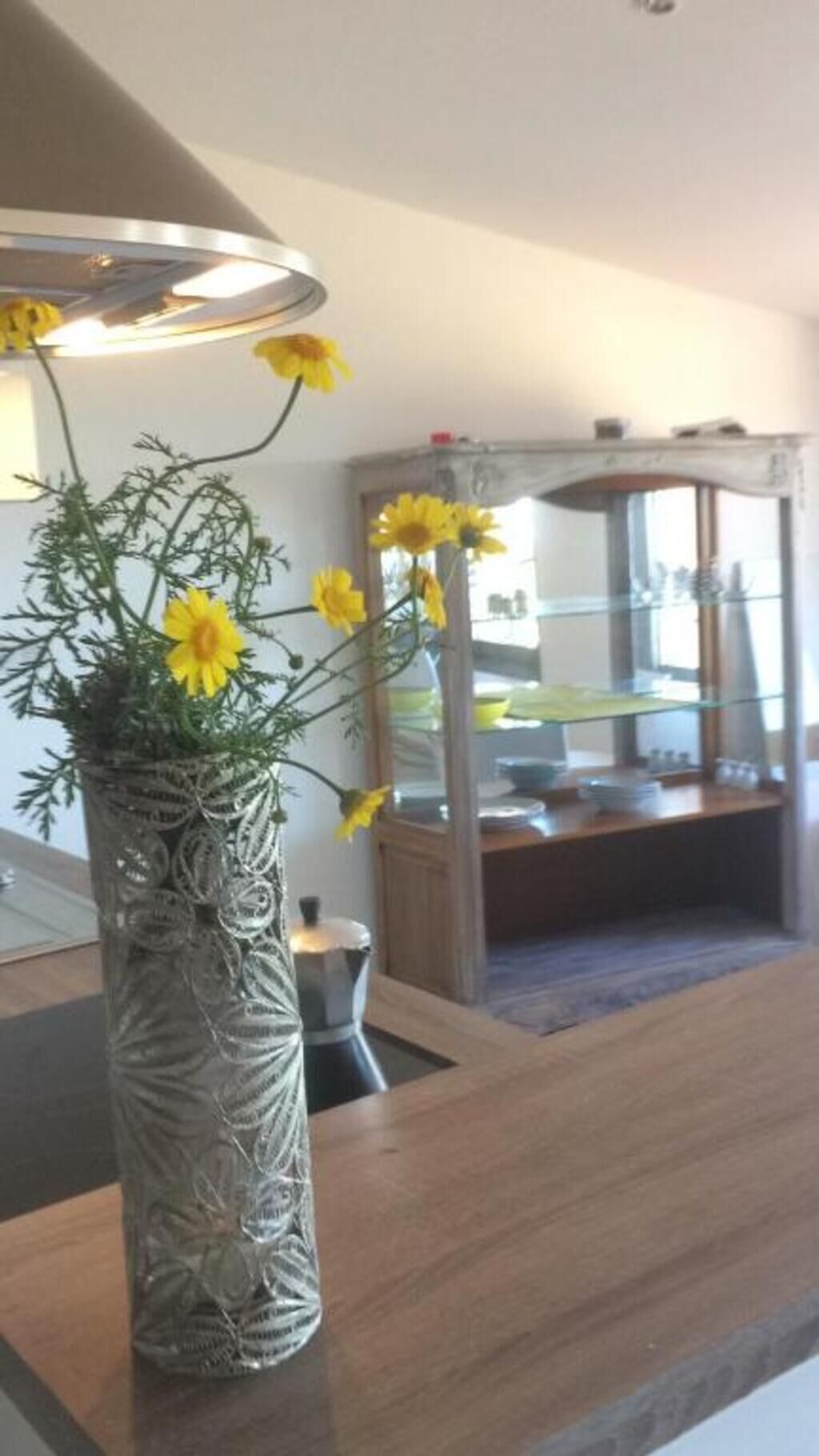 Ett rum med en trädisk, en dekorativ vas med gula blommor och en spegel som reflekterar rummet.
