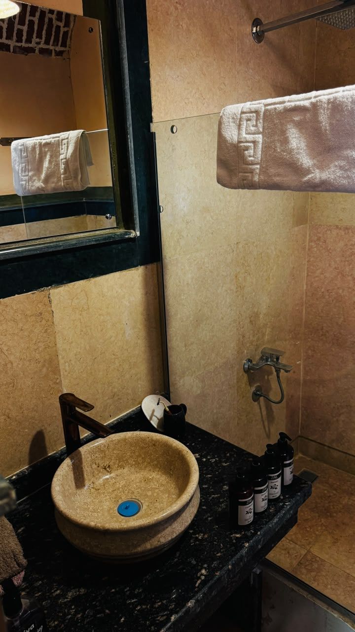 Un baño con un lavabo redondo, un perchero y un cabezal de ducha.