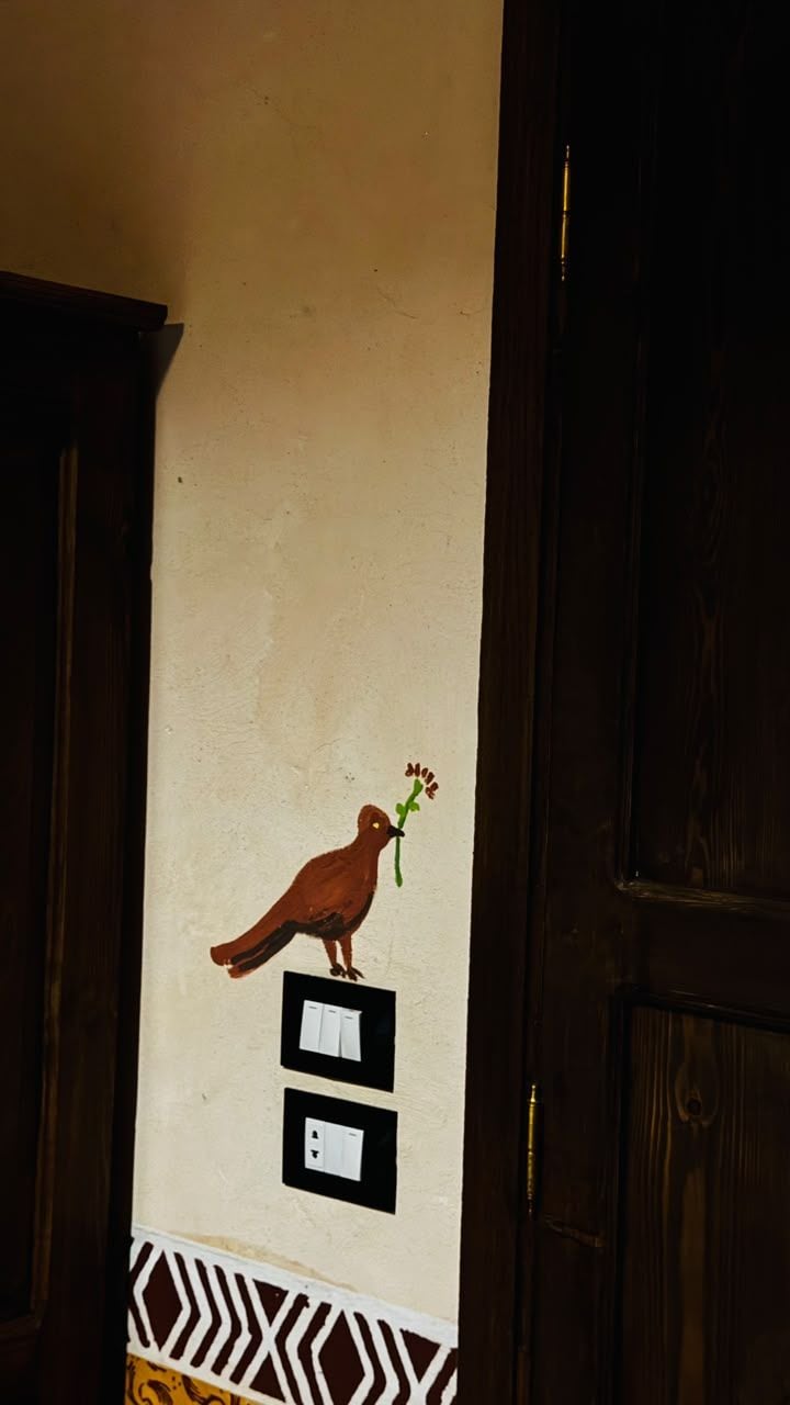 Pared con ilustración de un pájaro, dos interruptores de luz y un borde decorado.