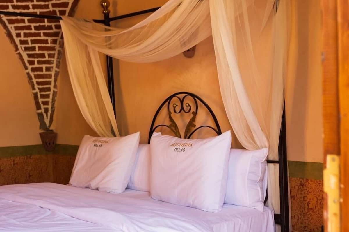 A bed with a canopy, a nightstand, and a brick wall.