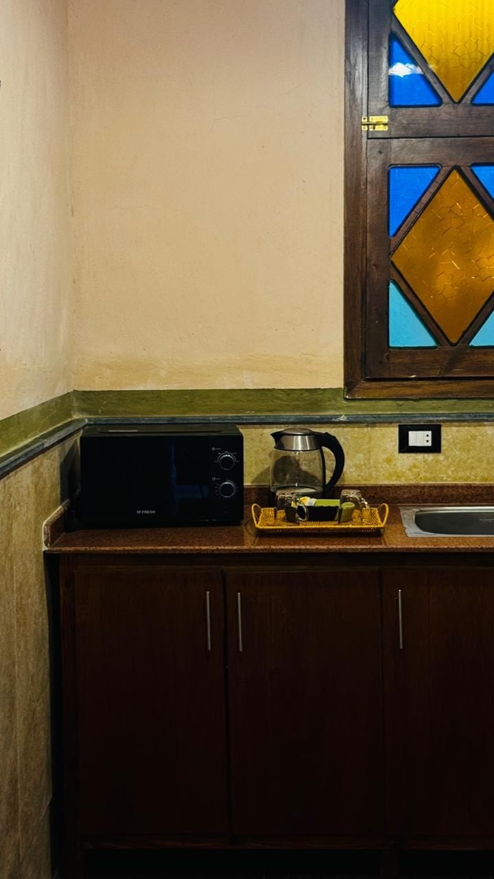 Une cuisine équipée d’un four à micro-ondes, d’une bouilloire et d’un évier. Un meuble est situé sous le plan de travail.