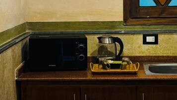 Une cuisine équipée d’un four à micro-ondes, d’une bouilloire et d’un évier. Un meuble est situé sous le plan de travail.