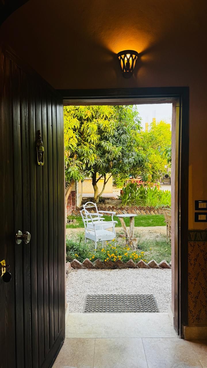 A doorway leading to a garden with a metal table and chairs, a tree, and a well-maintained lawn.
