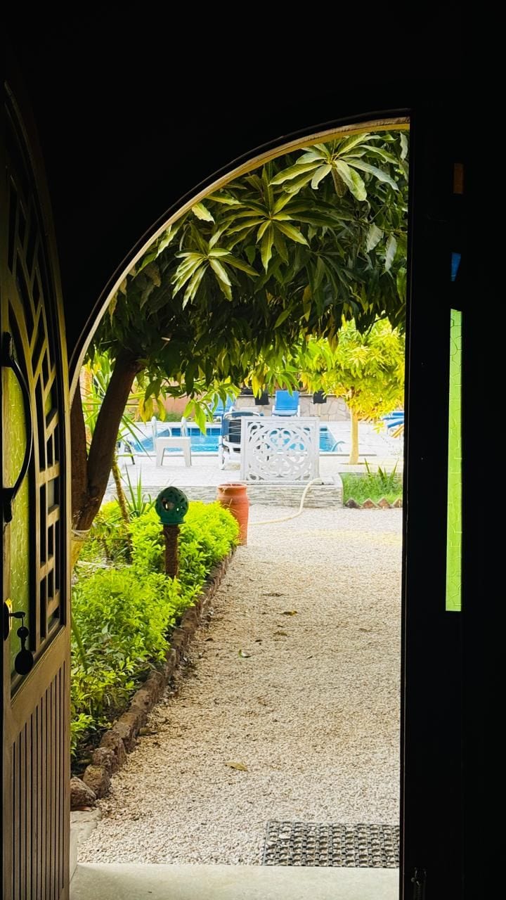 An outdoor pathway leading to a pool area with a covered seating area and a view of the pool.