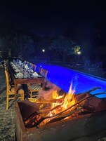 Un espacio de comedor al aire libre con piscina y un hogar para la chimenea.
