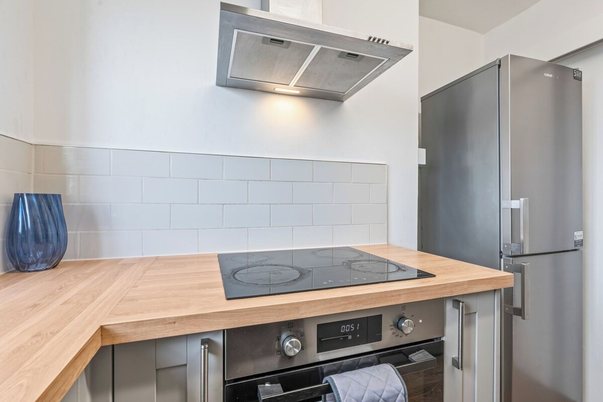 A kitchen with a built-in stove, oven, and stainless steel refrigerator.