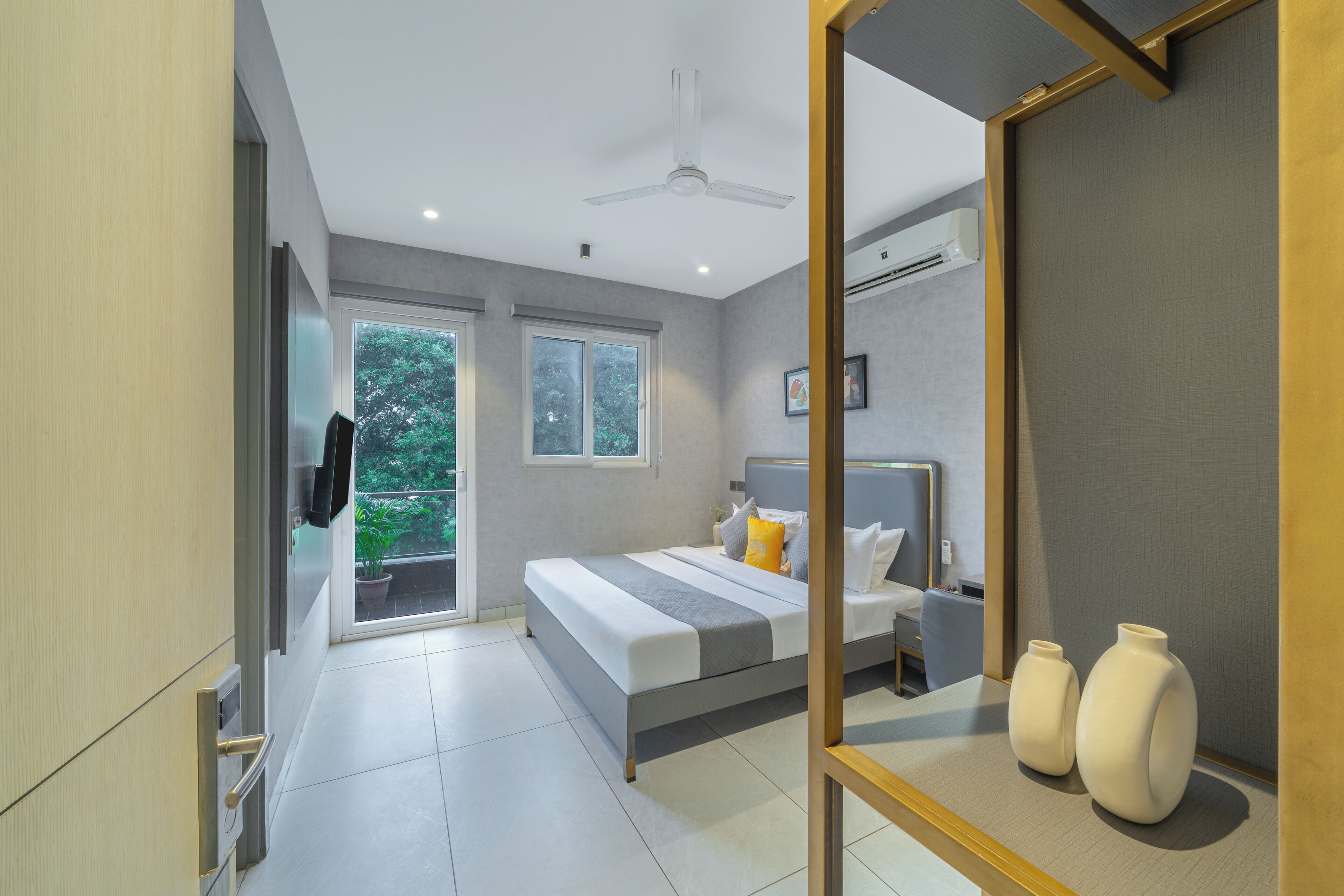 Un dormitorio moderno con cama, mesitas de noche, espejo y vistas a zonas verdes.