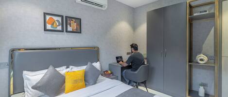 A modern bedroom with a bed, a desk, and a wardrobe.