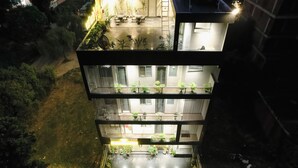 Un immeuble à plusieurs étages doté de balcons, d ’un espace extérieur aménagé pour s’asseoir et de plantes en pot.