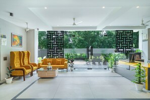 A spacious lobby with a modern yellow sofa set, a wooden coffee table, and potted plants. - Lime Tree Hotel & Stays Greater Noida Nearby India Expo Centre & Mart (Greater Noida)