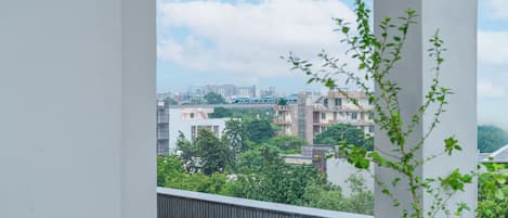 Un balcón con vista a un paisaje urbano, que incluye edificios y un puente distante.