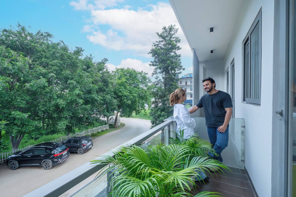 Ein Balkon mit Blick auf eine Straße und geparkte Autos, umgeben von Grün.