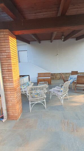 An outdoor patio with wicker furniture, a stone wall, and a wooden ceiling. - CASA AZZURRA Nice one-room apartment with terrace in Cilento. Pet friendly (Castellabate)