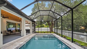 Ein Pool mit Glasverkleidung, umgeben von einer Terrasse mit Sitzgelegenheiten und Blick ins Freie.