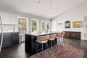 Een moderne keuken met een centraal eiland, barstoelen en een vloerkleed met een patroon.