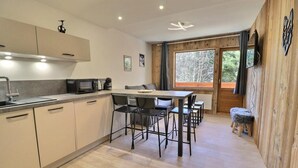Una cocina moderna con comedor, paredes de madera y un ventanal grande.