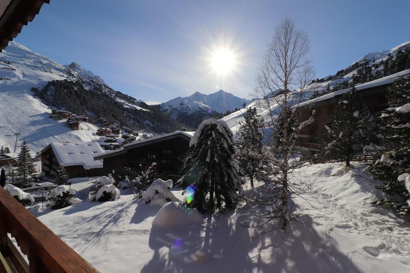 A snow-covered mountain landscape with a wooden cabin and a tree in the foreground.