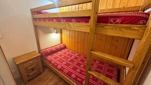 A bunk bed with a red patterned mattress and a wooden headboard.