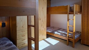 Une chambre avec un lit superposé en bois, une échelle et un petit bureau.