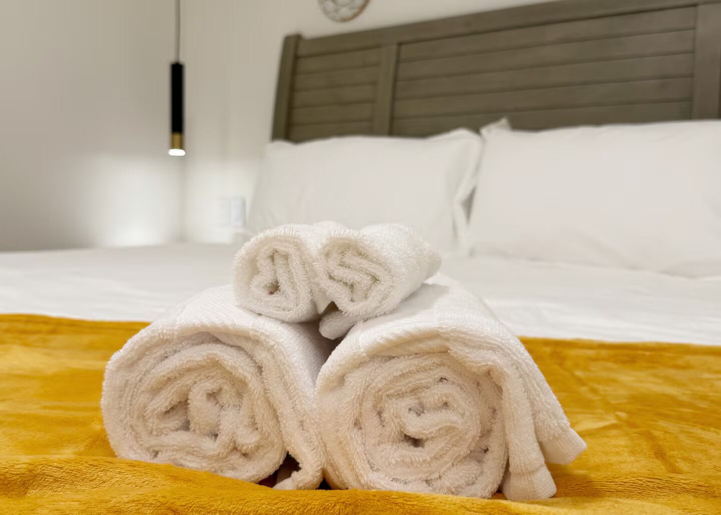 A neatly made bed with white linens and a yellow blanket.