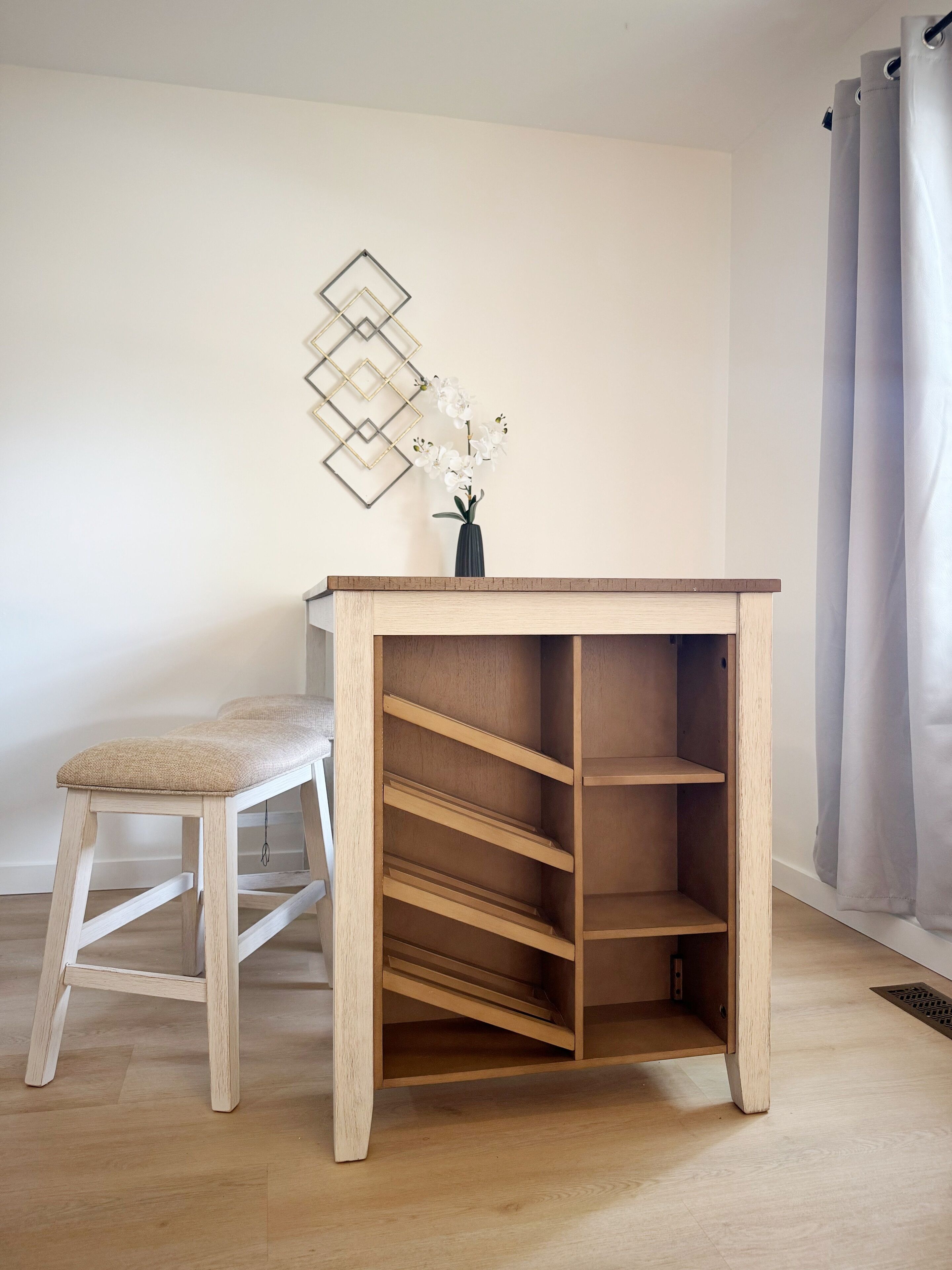 Un escritorio de madera con estantes, un taburete acolchado y un florero con flores.