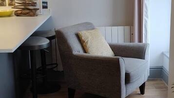 A corner seating area with a grey armchair and a small round table.