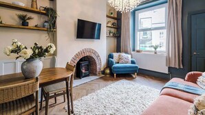 A living room with a fireplace, a television, a blue sofa, and a chandelier.