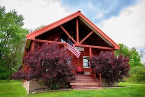 Eine rote Holzhütte mit Veranda, Treppen und einer amerikanischen Flagge.